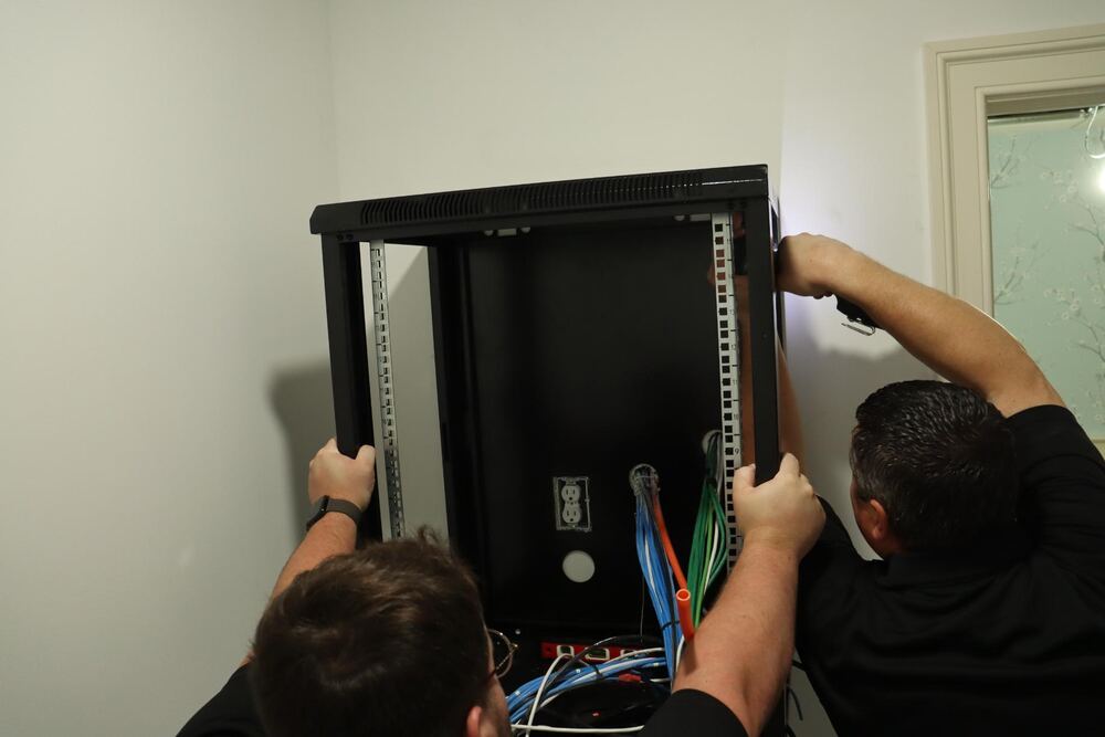 Technicians mounting a wall network rack cabinet