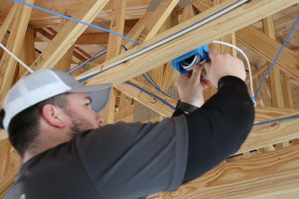 Technician installing network cable box in ceiling joists